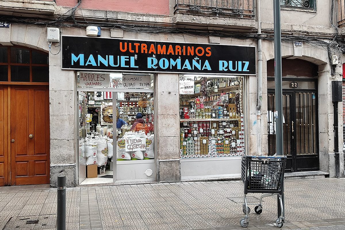 Fachada de una tienda de ultramarinos de barrio en Bilbao, con escaparate de productos y puerta de madera