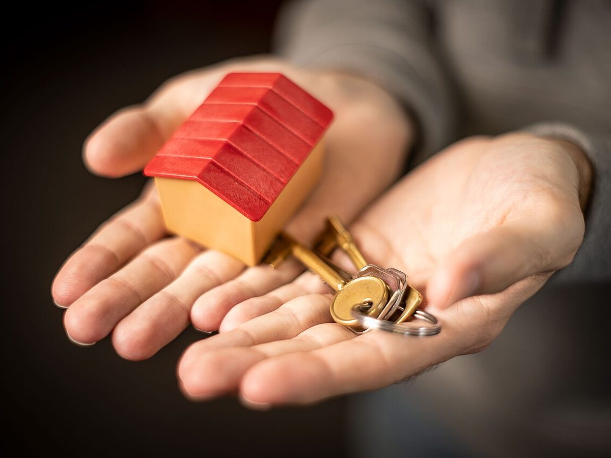 Manos sosteniendo una maqueta de vivienda y un manojo de llaves