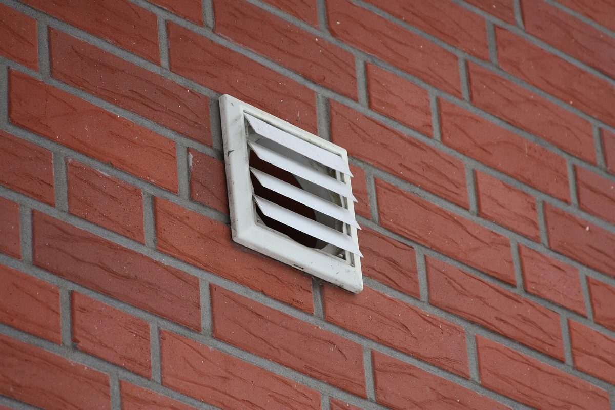 Rejilla de ventilación en la fachada de ladrillo de una vivienda
